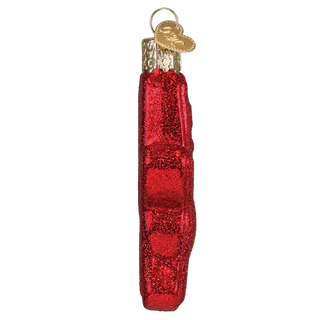 Red glass ornament shaped like a loaf of bread with a gold tag on a white background
