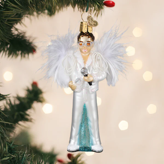 Decorative Christmas ornament of Elton John in a white outfit with wings, holding a microphone, on a blurred Christmas tree background.