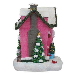 Decorative Christmas house with pink walls, snow-covered roof, and festive trees on a white background.