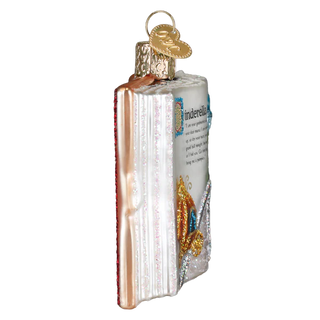 Decorative glass ornament shaped like a book with a gold ribbon on a white background