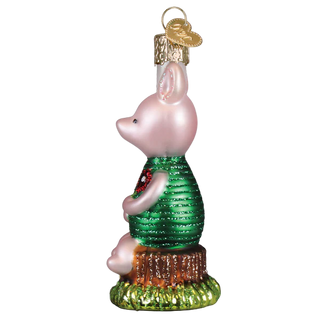 Glass ornament of Piglet in a green sweater with a red bow, on a white background.